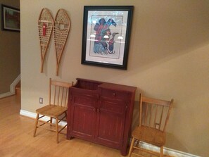 A room with a wooden bench, a red cabinet, and two wall-mounted skis.