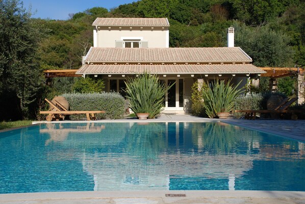 Una casa a due piani con piscina di fronte.