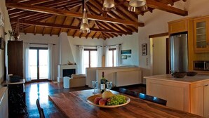 A spacious kitchen with wooden beams, a central island with fruit, and modern appliances.