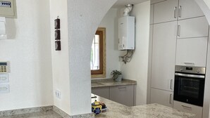 Una cocina con encimera de granito, armarios blancos, horno empotrado y microondas.
