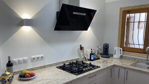 Una cocina moderna con estufa a gas, televisor de pantalla plana y ventana con marco de madera.