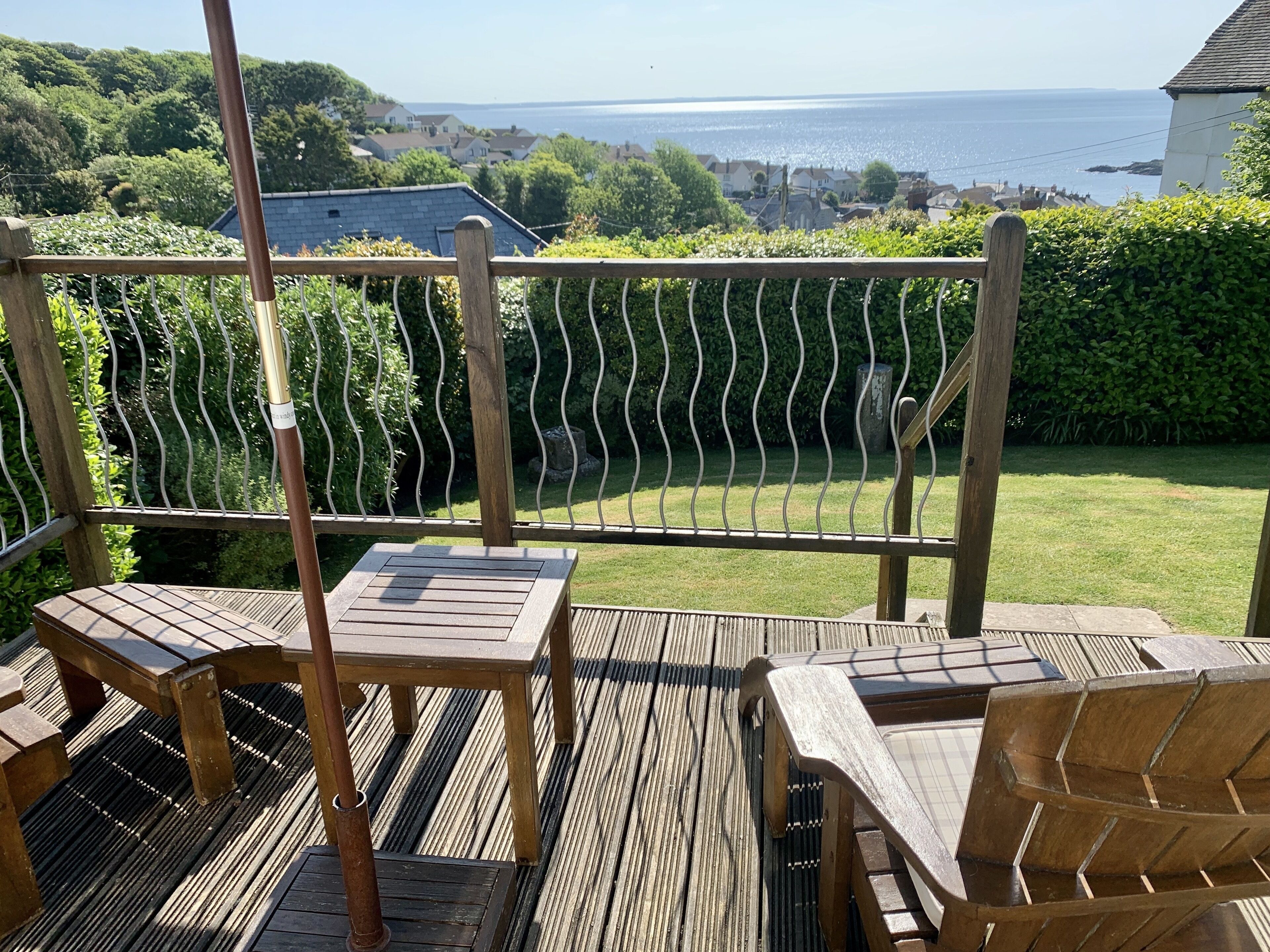 A wooden deck with a view of the sea and houses in the background.