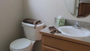 Une salle de bain avec des toilettes, un lavabo et un miroir.