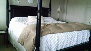Un lit à baldaquin avec une couverture beige, une courtepointe blanche et une décoration en forme d’étoile de mer sur le mur.