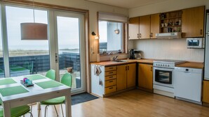 Ett modernt kök med träskåp, en inbyggd mikrovågsugn och ett stort fönster med utsikt över ett vackert landskap.