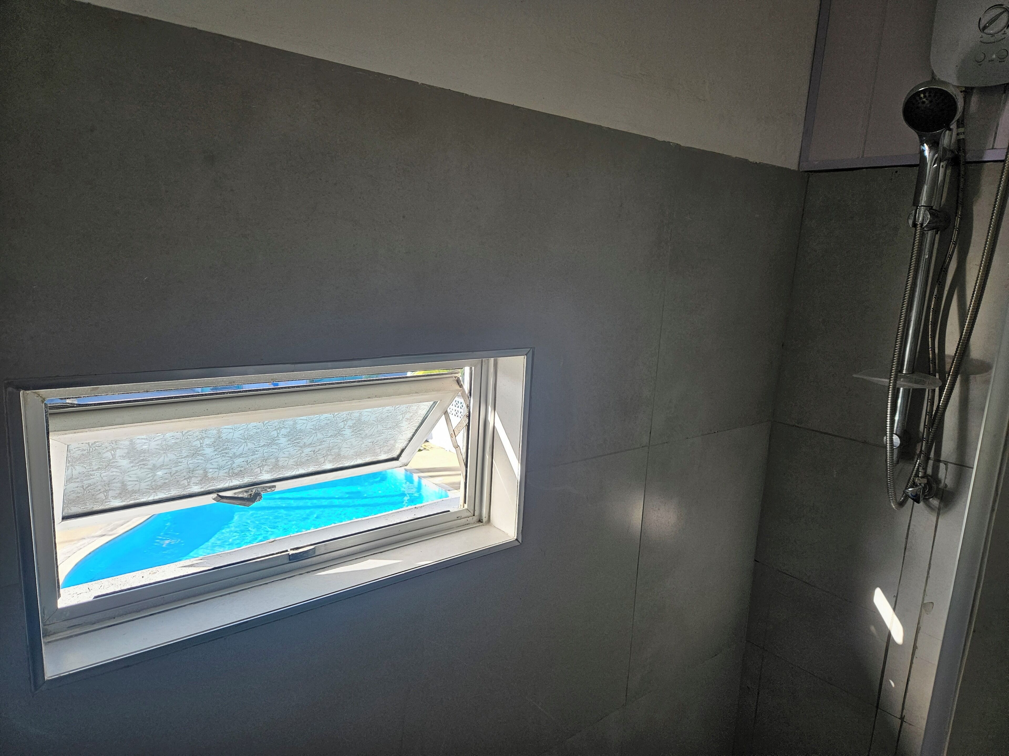 Ein Badezimmer mit Oberlicht, Dusche und Blick auf einen Pool.