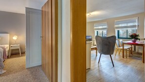 A modern living room with a wooden floor, a dining area with a table and chairs, and a bedroom with a bed and a lamp. - Vacation under the thatched roof on the backwater opposite the island of Usedom (Lassan)