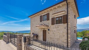 A stone building with a tiled roof, a wooden door, and a metal gate. - Villa CAVALLO with pool and sea view (Linardići)