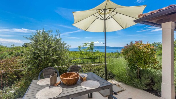 An outdoor dining area with a table, chairs, and a large umbrella. - Villa CAVALLO with pool and sea view (Linardići)