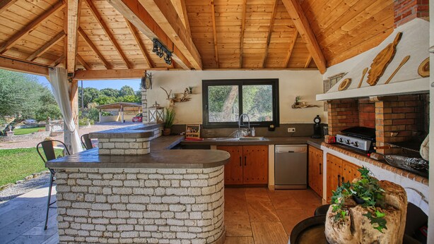 Une cuisine rustique avec un îlot central en pierre, des armoires en bois et un four en briques.
