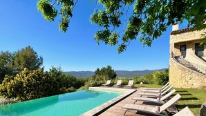 Ein Pool mit klarem, blauem Wasser, umgeben von Holzliegen und einem Gebäude mit einer Steintreppe.