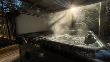 Ein Whirlpool mit aufsteigendem Dampf, umgeben von einer Holzdielen-Terrasse und einem Metallgeländer.