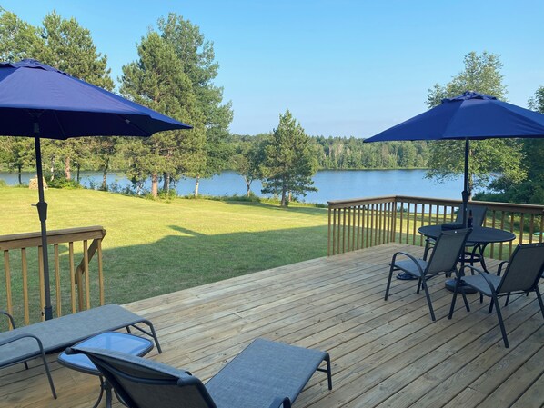 Une terrasse dotée de mobilier d’extérieur, notamment des chaises et une table, donnant sur un lac.