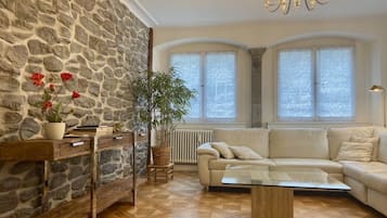 Ein Wohnzimmer mit Steinsandsteinwand, einer Couch, einem Couchtisch und einer Kristalllüster.
