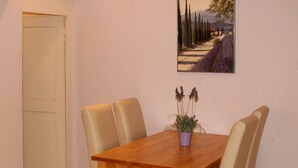 A dining table with four chairs, a potted plant, and a painting on the wall. - Apartment Lindauer Löwe- Charming, close to the lake & central in a historic building (Lindau)