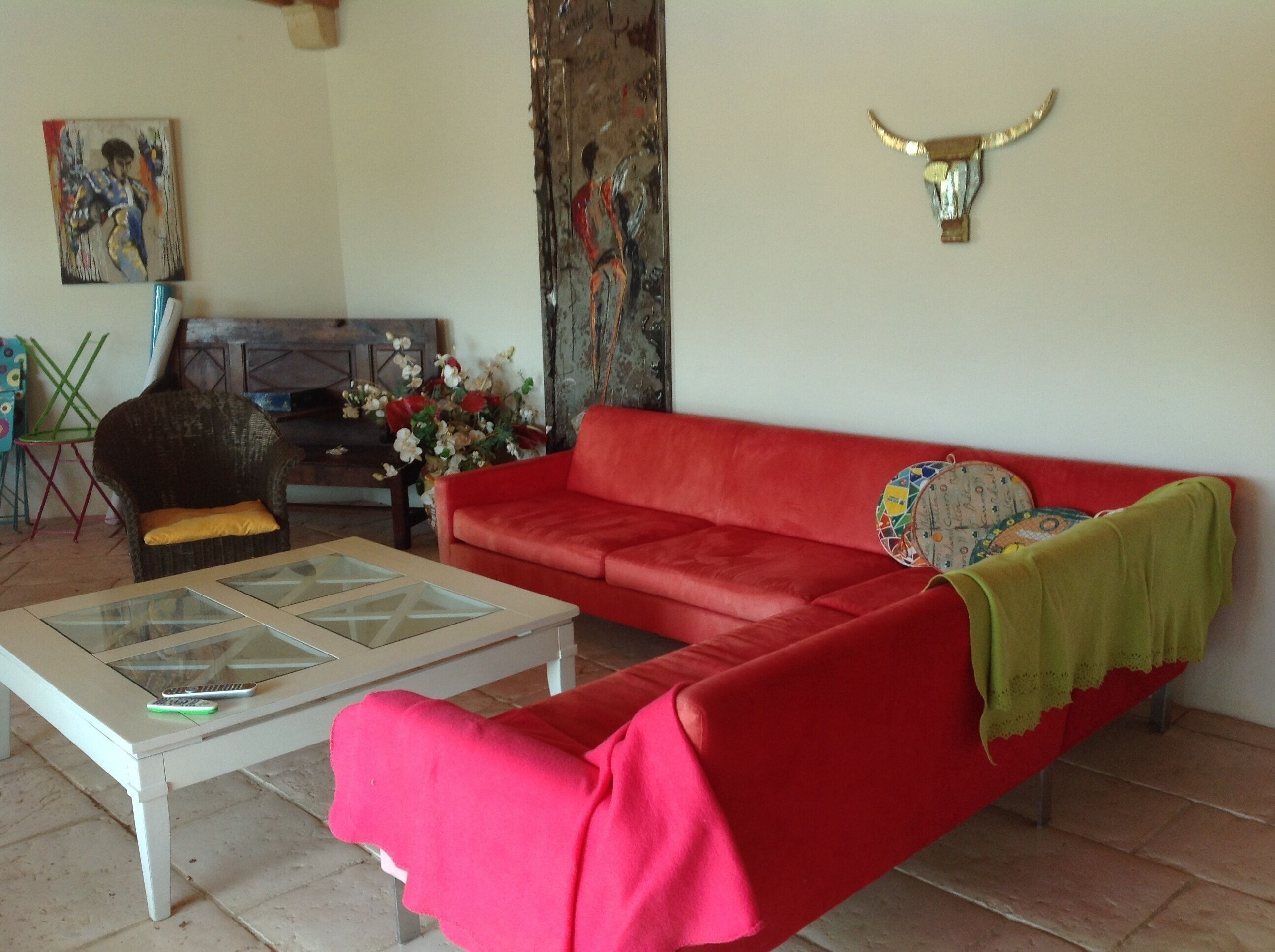 Una sala de estar con un sofá rojo, una mesa de centro de vidrio y una cabeza de toro decorativa en la pared.