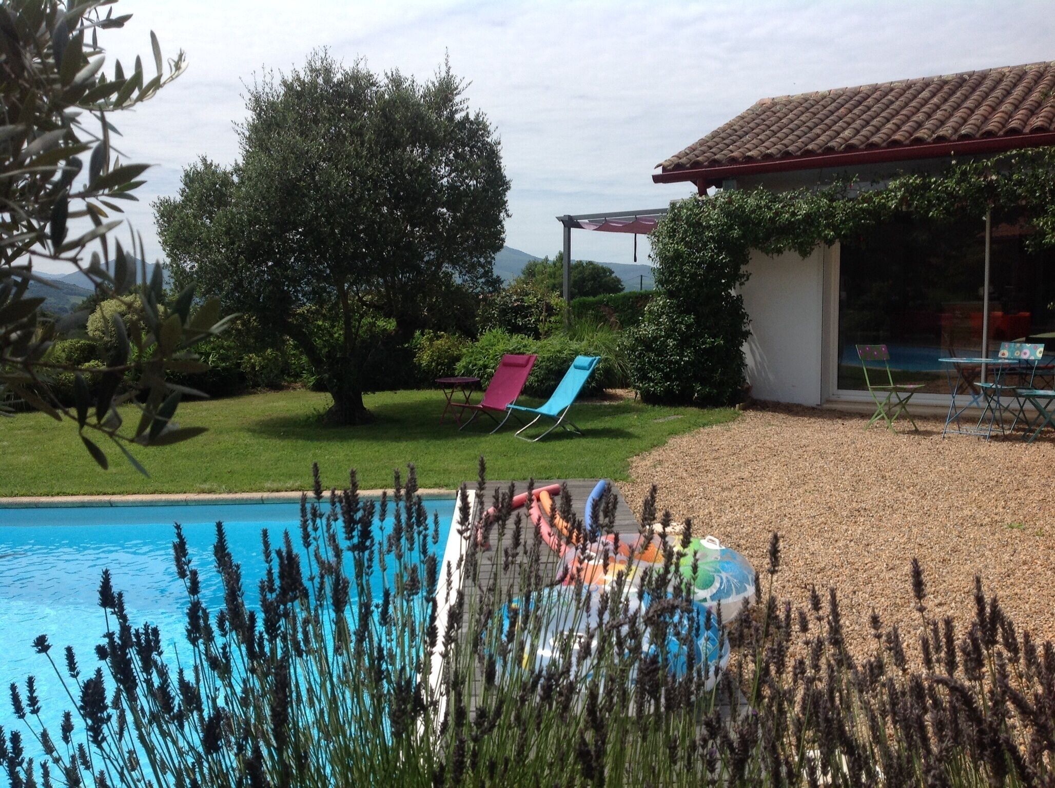 A swimming pool with lounge chairs, a covered patio, and a view of the surrounding landscape.