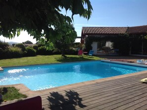 A rectangular swimming pool with clear blue water, surrounded by a wooden deck. - Studio beautiful view of the Pyrenees  (Souraïde)