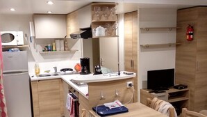 A compact kitchen with a microwave, coffee maker, and a TV.