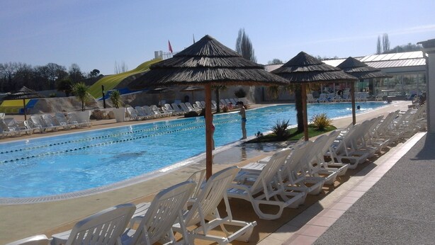 A swimming pool with multiple lanes, sun loungers, and thatched umbrellas.