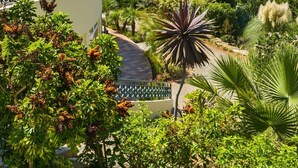 Un resort con zona de piscina, rodeado de exuberante vegetación y un edificio de varios pisos con balcones.
