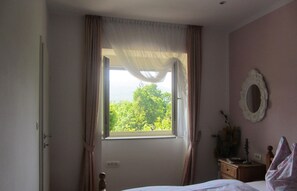 A bedroom with a bed, a window with sheer curtains, a bedside table with a lamp, and a mirror on the wall. - Apartment Mirjana - Mali Brgud - surrounded by greenery, ideal for families (Jurdani)