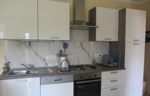 A kitchen with white cabinets, a gas stove, a dishwasher, and a microwave. - Apartment Mirjana - Mali Brgud - surrounded by greenery, ideal for families (Jurdani)