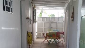 A corridor with a table and chairs, a suitcase, and a window with a geometric pattern.