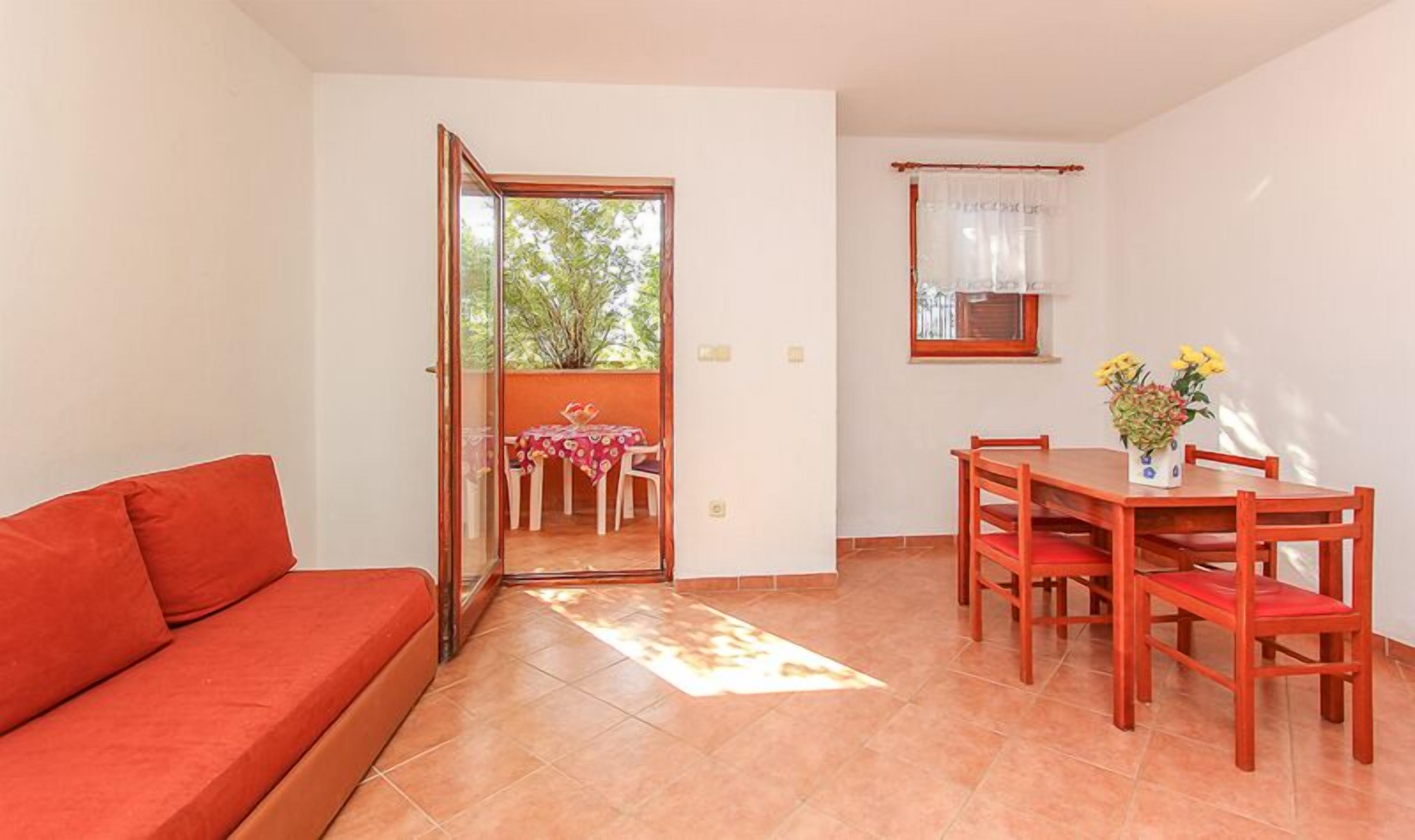 A compact living space with a sofa, a dining table with chairs, and a small window with curtains.