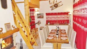 Ein Essbereich mit einem Holztisch, gedeckt für vier Personen, einem Kamin und einer Treppe.