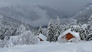 Eine verschneite Landschaft mit einer Holzhütte und Bäumen.