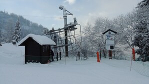 Eine verschneite Talstation einer Seilbahn mit einer Holzhütte und einem Schild, das die Stilllegung der Bahn anzeigt.