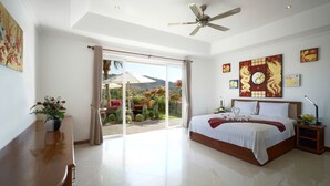 A spacious bedroom with a large bed, a ceiling fan, and a view of a garden through a sliding glass door. - Luxurious, quiet, private Pool-Villa Jasmine, 7/7 housekeeper/butler (Phuket)