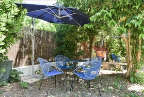 Relax in a garden setting with a shaded patio featuring a table and comfortable seating for four.
