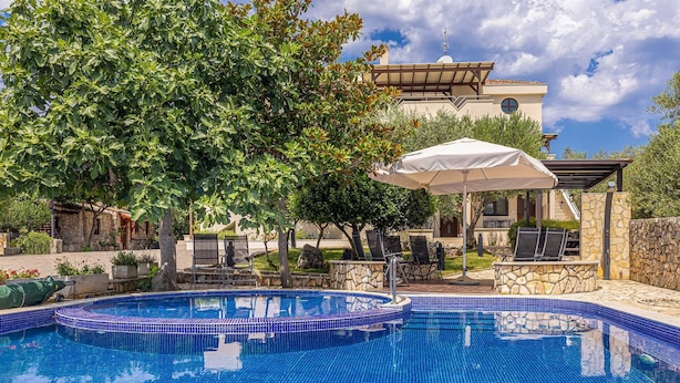 Une piscine dont le bord est revêtu de carrelage, entourée de chaises longues et d’un parasol.
