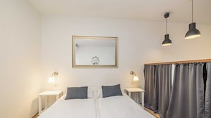 Une chambre d’hôtel avec un grand lit, deux tables de chevet avec des lampes, un miroir et un rideau.