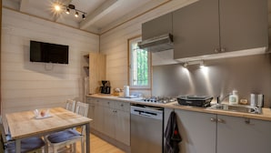A compact kitchen with a wooden table, chairs, a built-in stove, and a window providing natural light. - Vacation rental in self-catering village with heated swimming pool near Sarlat (Orliaguet)