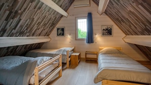 A dormitory room with three bunk beds, wooden beams on the ceiling, a window with a curtain, and two wall-mounted pictures. - Vacation rental in self-catering village with heated swimming pool near Sarlat (Orliaguet)