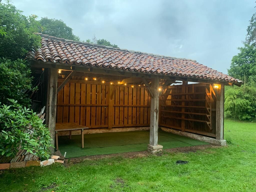 A wooden gazebo with a tiled roof and string lights.