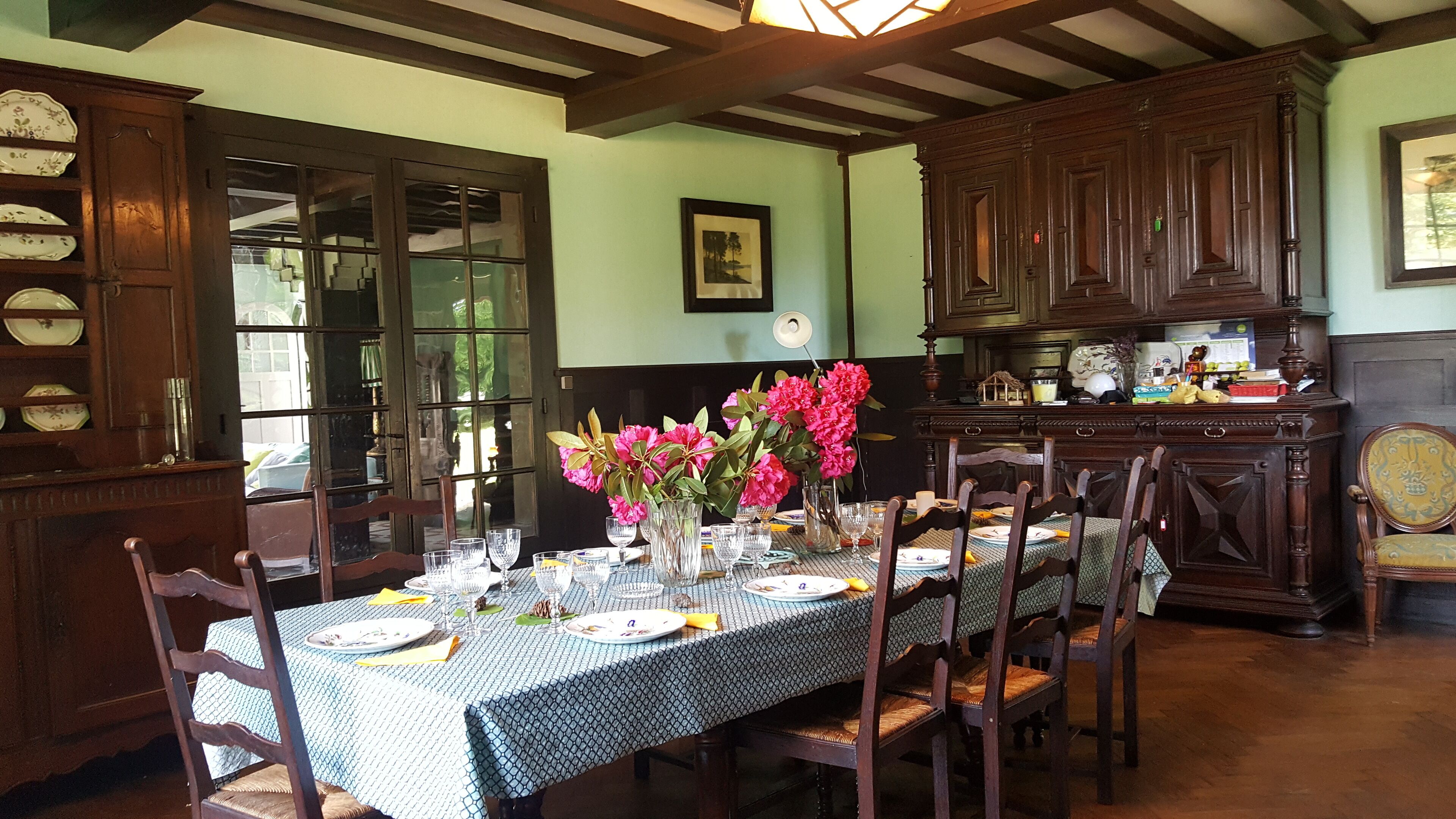 A dining room with a table set for four, surrounded by wooden chairs.