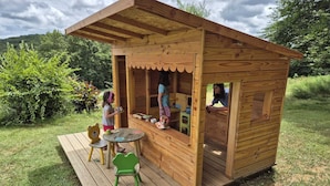 Une maisonnette en bois avec une véranda, une petite table et des chaises.