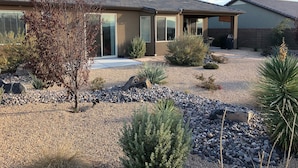 A modern house with a patio, surrounded by a gravel garden with various plants and rocks. -  CORAL CANYON VIEW HOME !!!! UP ON THE LEDGE! DOG FRIENDLY! (Washington City)