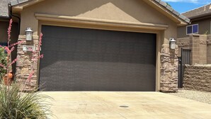 A residential garage with a dark-colored door, stone pillars, and a clear blue sky in the background. -  CORAL CANYON VIEW HOME !!!! UP ON THE LEDGE! DOG FRIENDLY! (Washington City)