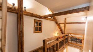 Una escalera de madera con barandilla y un ventanal pequeño.