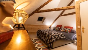 Un dormitorio con cama, lámpara y techo de madera.
