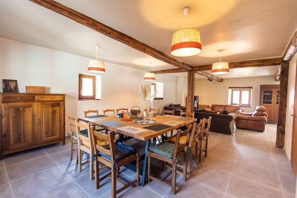 Un comedor espacioso con una mesa y sillas de madera, un armario de madera y un sofá al fondo.