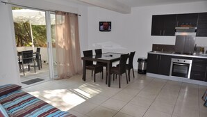 A modern apartment with a dining area, kitchen, and a balcony with a sliding door. - Turquoise apartment 4/5 people (San-Nicolao)