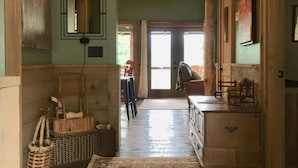 Un couloir avec un tapis à motifs, un luminaire au plafond et un miroir accroché au mur.