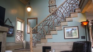 Un escalier au design en bois agrémenté d’éléments décoratifs, un tableau encadré accroché au mur et un vase posé sur une étagère.