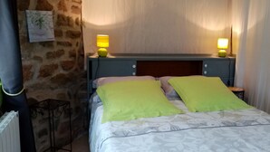 Een net opgemaakt bed met twee kussens, een hoofdbord en twee bedlampjes.